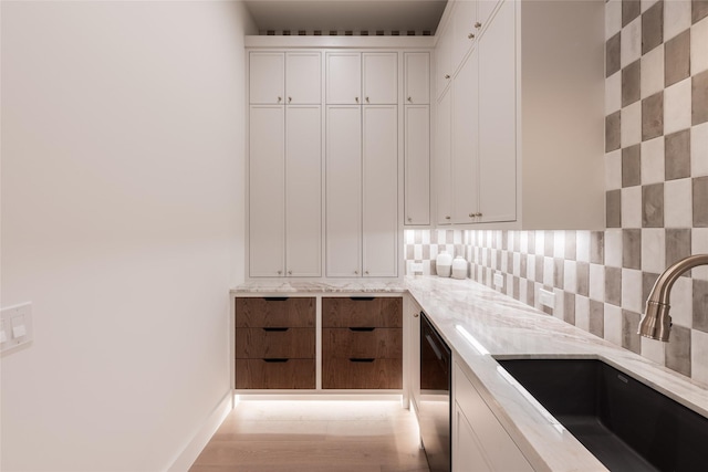 interior space featuring dishwasher, backsplash, and a sink