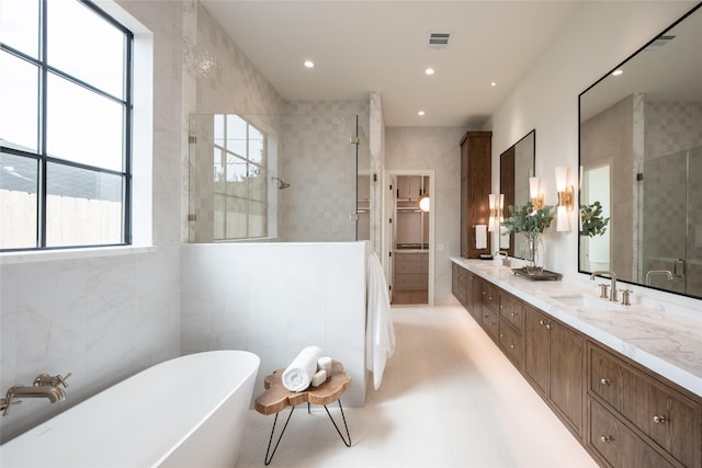 bathroom with a sink, tile walls, visible vents, a freestanding bath, and a tile shower