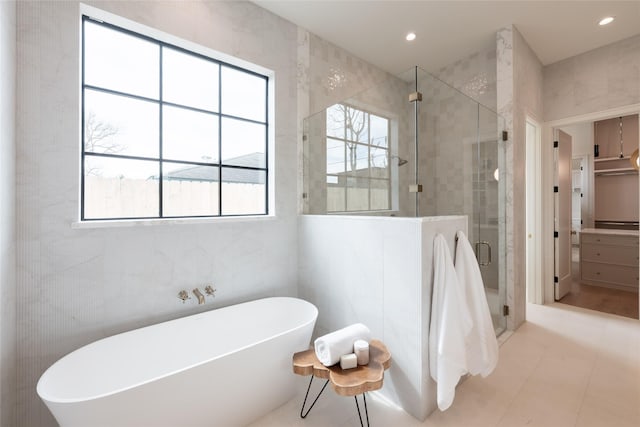 bathroom with a stall shower, a freestanding tub, and tile walls