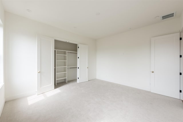 unfurnished bedroom with light colored carpet, a closet, visible vents, and baseboards