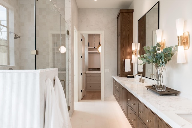 bathroom with tile patterned flooring, a sink, a spacious closet, double vanity, and a stall shower