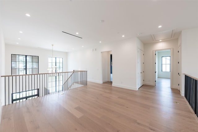 spare room featuring light wood finished floors, attic access, baseboards, and recessed lighting