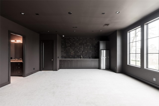 empty room featuring recessed lighting, a sink, visible vents, and light colored carpet