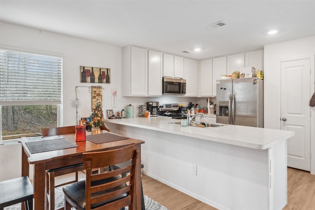 kitchen featuring appliances with stainless steel finishes, light countertops, a sink, and a peninsula