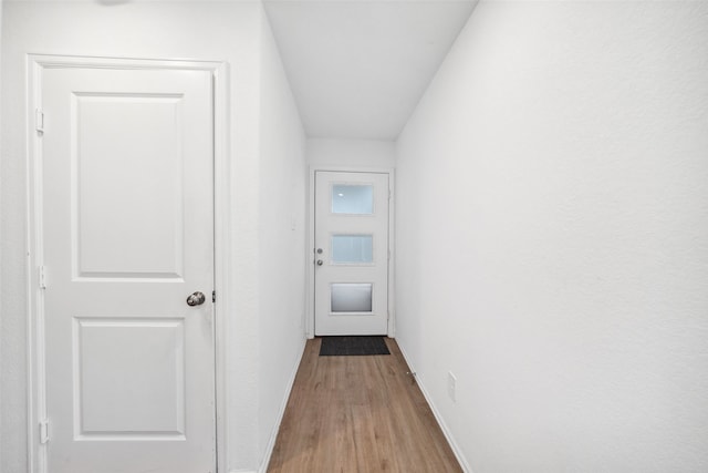 doorway to outside with wood finished floors and baseboards