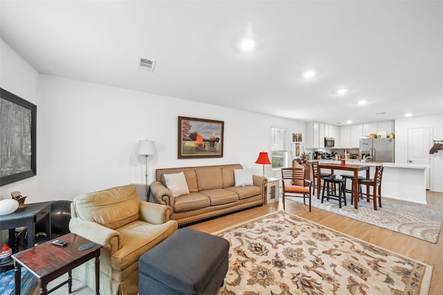 living room with light wood-style flooring, visible vents, and recessed lighting