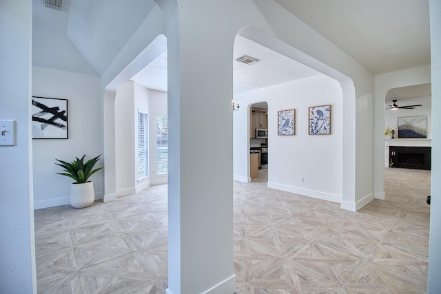 hall with baseboards, visible vents, and arched walkways