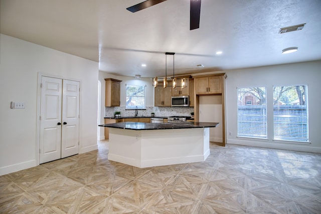 kitchen with dark countertops, stainless steel microwave, visible vents, and decorative backsplash