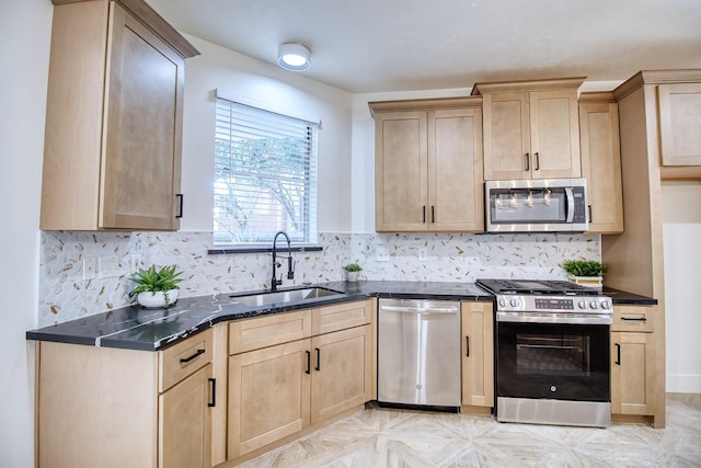 kitchen featuring decorative backsplash, dark stone countertops, stainless steel appliances, light brown cabinetry, and a sink