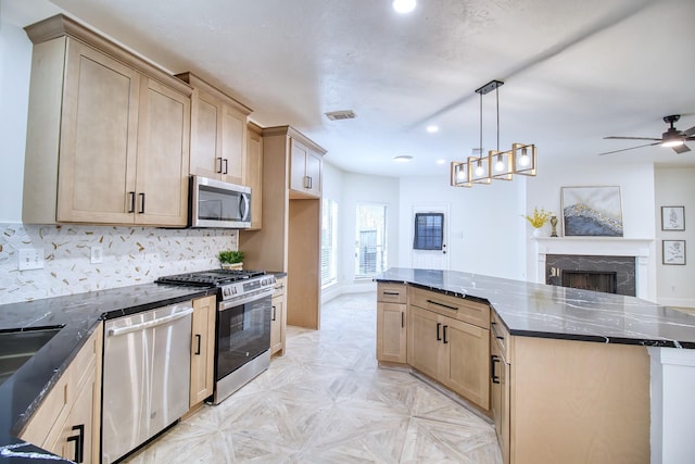 kitchen with appliances with stainless steel finishes, dark stone counters, visible vents, and a premium fireplace