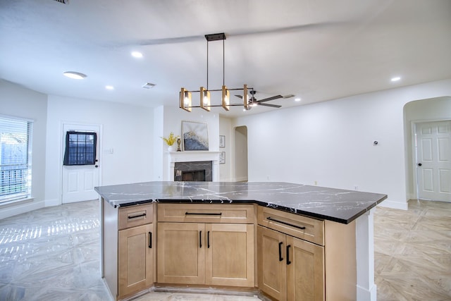 kitchen with baseboards, a fireplace, arched walkways, and recessed lighting