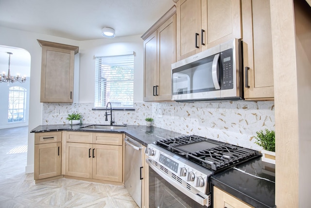 kitchen featuring appliances with stainless steel finishes, a healthy amount of sunlight, a sink, and light brown cabinets