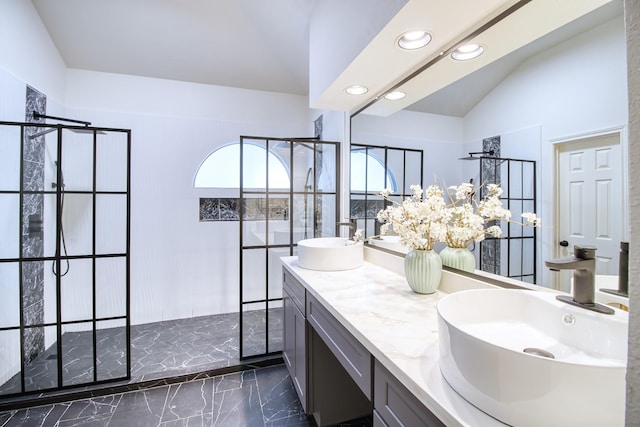 bathroom with marble finish floor, double vanity, a sink, and a walk in shower