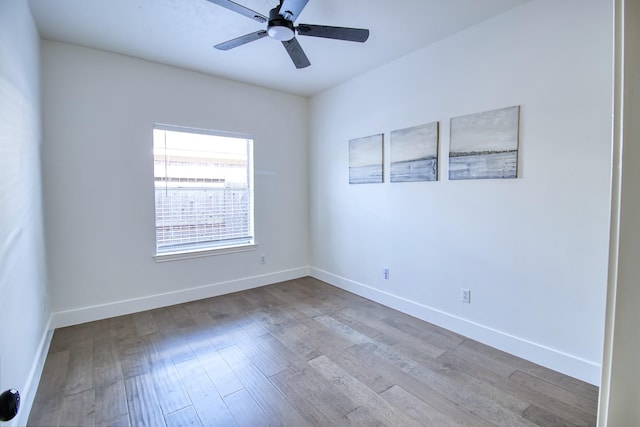 empty room with wood finished floors, a ceiling fan, and baseboards