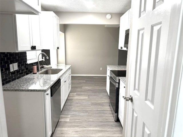 kitchen with light wood finished floors, tasteful backsplash, stainless steel appliances, white cabinetry, and a sink