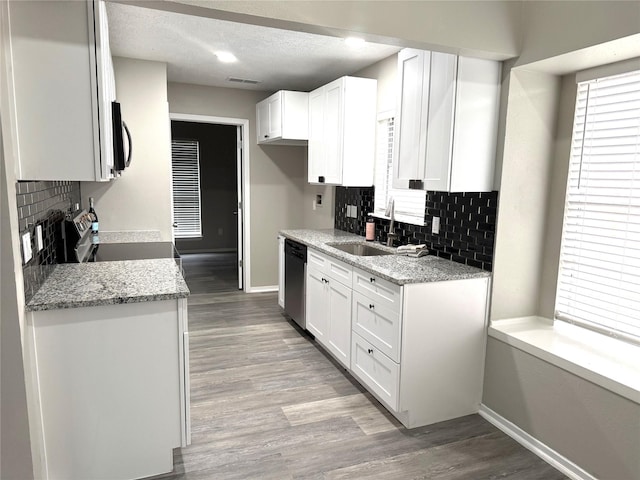 kitchen with visible vents, light wood-style flooring, appliances with stainless steel finishes, white cabinetry, and a sink