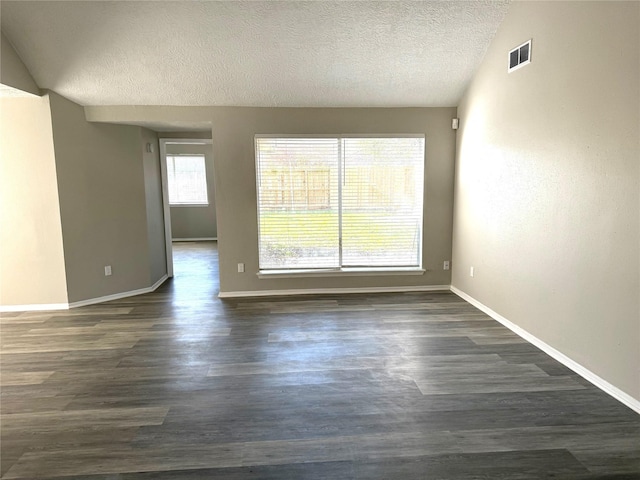 spare room featuring baseboards, a textured ceiling, visible vents, and dark wood-type flooring