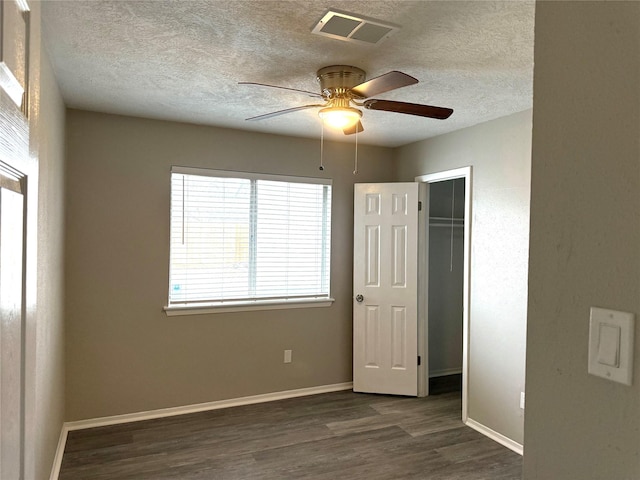 unfurnished bedroom with dark wood-style floors, a textured ceiling, visible vents, and baseboards