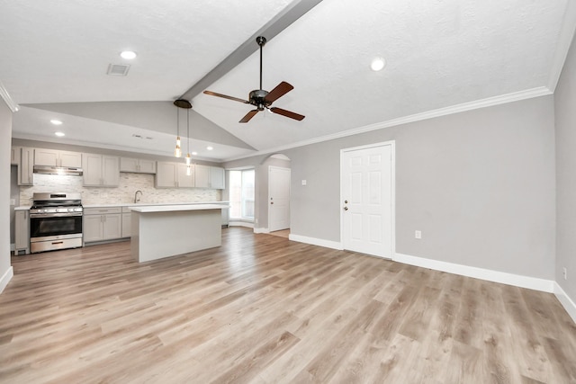 kitchen with arched walkways, light wood-type flooring, gray cabinets, stainless steel range with gas cooktop, and tasteful backsplash