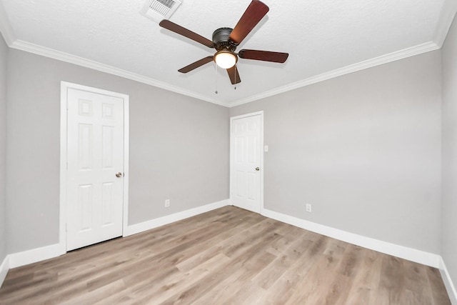 spare room with visible vents, crown molding, baseboards, and wood finished floors