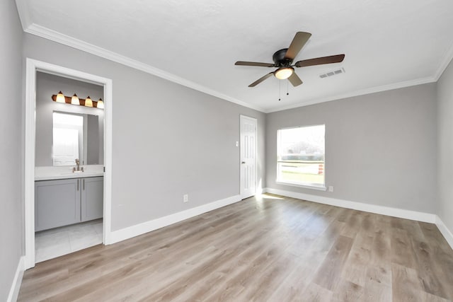 empty room featuring ornamental molding, visible vents, light wood-style flooring, and baseboards