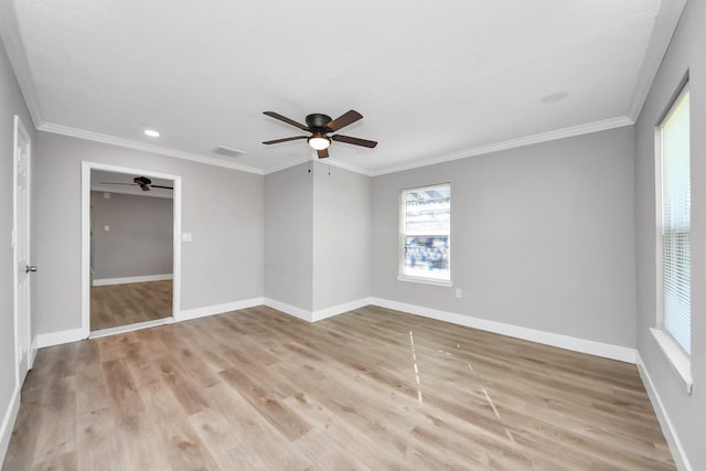 spare room with light wood-style floors, visible vents, crown molding, and baseboards