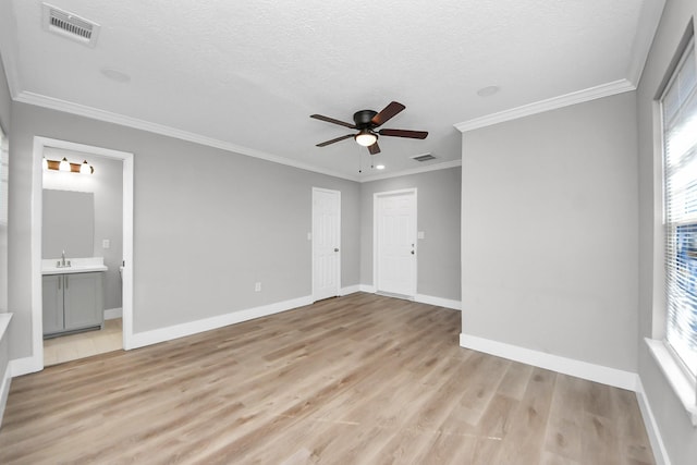 unfurnished bedroom with baseboards, visible vents, light wood-style flooring, a textured ceiling, and a sink