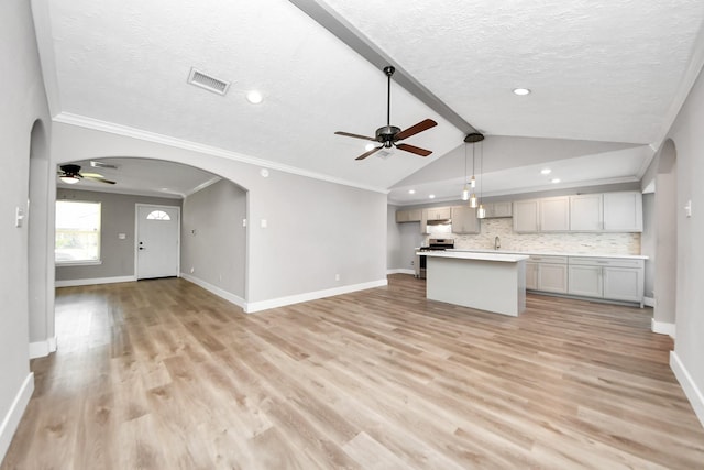 kitchen with arched walkways, stainless steel stove, visible vents, decorative backsplash, and open floor plan