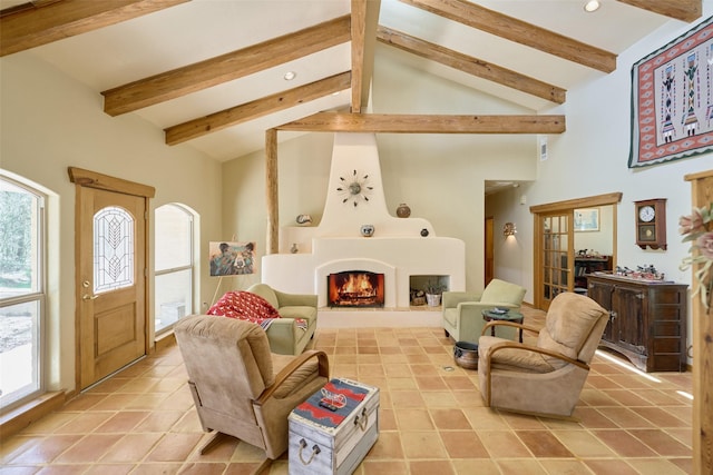 living area with plenty of natural light, beamed ceiling, high vaulted ceiling, and a large fireplace