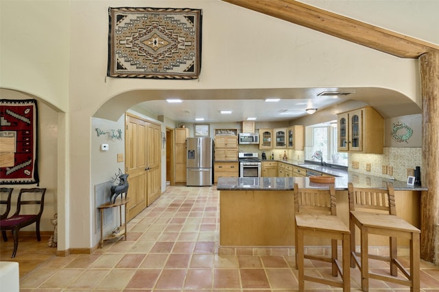 kitchen with glass insert cabinets, tasteful backsplash, appliances with stainless steel finishes, and a peninsula