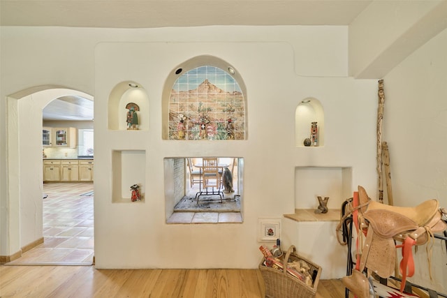 corridor featuring arched walkways and light wood finished floors