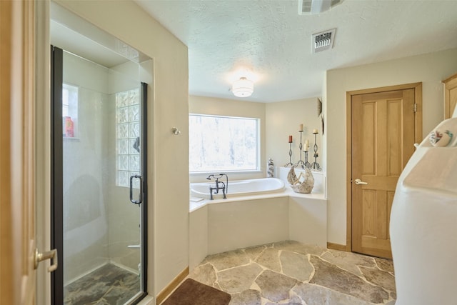 full bathroom featuring visible vents, a stall shower, stone finish floor, a textured ceiling, and a garden tub