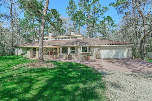 view of front of property featuring driveway, a tile roof, a front yard, a garage, and a chimney