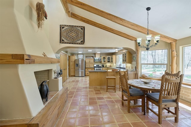 dining space featuring arched walkways, beam ceiling, a fireplace with raised hearth, and an inviting chandelier