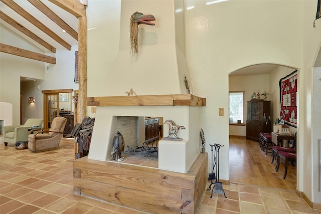 interior space with baseboards, high vaulted ceiling, arched walkways, tile patterned floors, and beamed ceiling