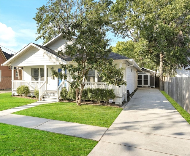 bungalow-style house with covered porch, driveway, a front yard, and fence