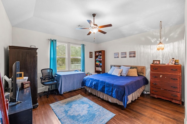 bedroom featuring a tray ceiling, lofted ceiling, visible vents, ceiling fan, and wood finished floors