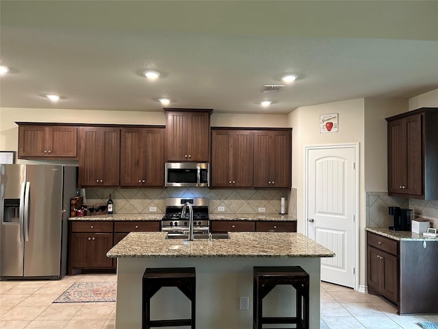 kitchen featuring visible vents, appliances with stainless steel finishes, light stone counters, a sink, and light tile patterned flooring