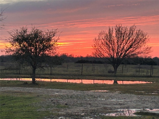 view of yard with a rural view, a water view, and fence