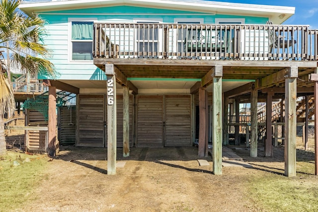 back of house featuring stairway, a carport, and a wooden deck