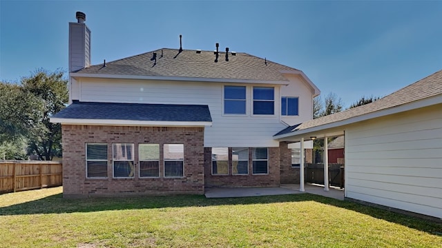 back of house with brick siding, a patio, a lawn, and fence