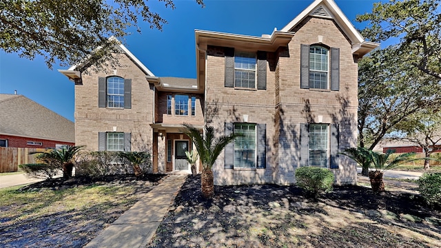 view of front of home with brick siding and fence