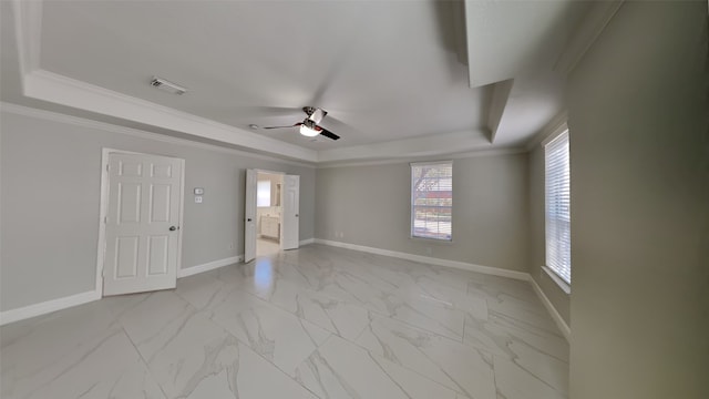 spare room with ornamental molding, marble finish floor, a tray ceiling, and baseboards