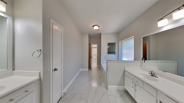 bathroom with marble finish floor, two vanities, a sink, and baseboards