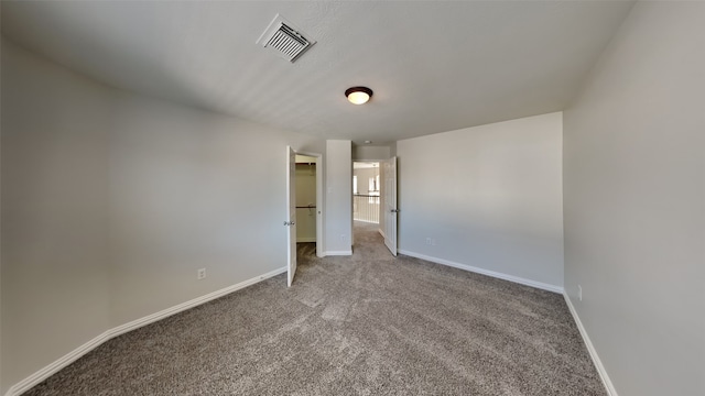 unfurnished bedroom with baseboards, visible vents, a spacious closet, and carpet flooring