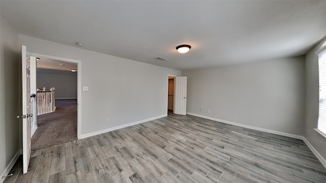 spare room with light wood finished floors, plenty of natural light, and visible vents