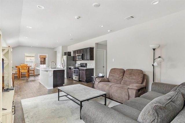 living area with dark wood-style floors, lofted ceiling, visible vents, and recessed lighting