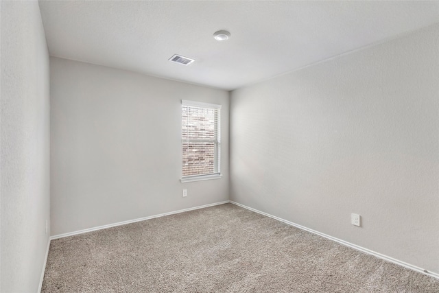 spare room with carpet floors, visible vents, and baseboards