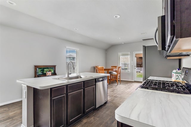 kitchen featuring dark wood-type flooring, a sink, light countertops, appliances with stainless steel finishes, and an island with sink