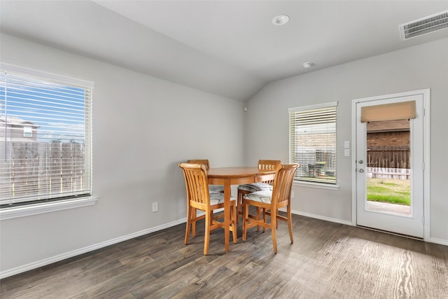 dining room with baseboards, visible vents, vaulted ceiling, and wood finished floors